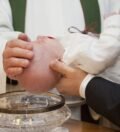pastor laying a hand on baby's head during baptism