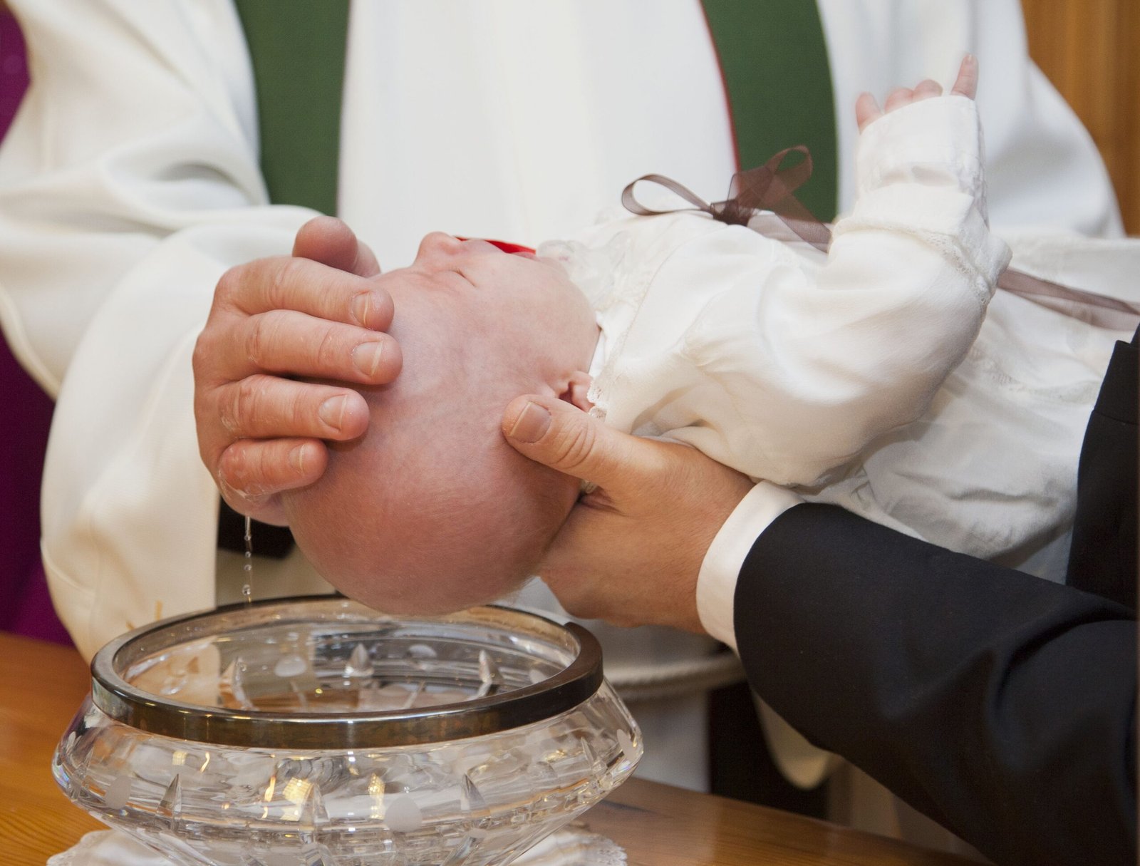pastor laying a hand on baby's head during baptism
